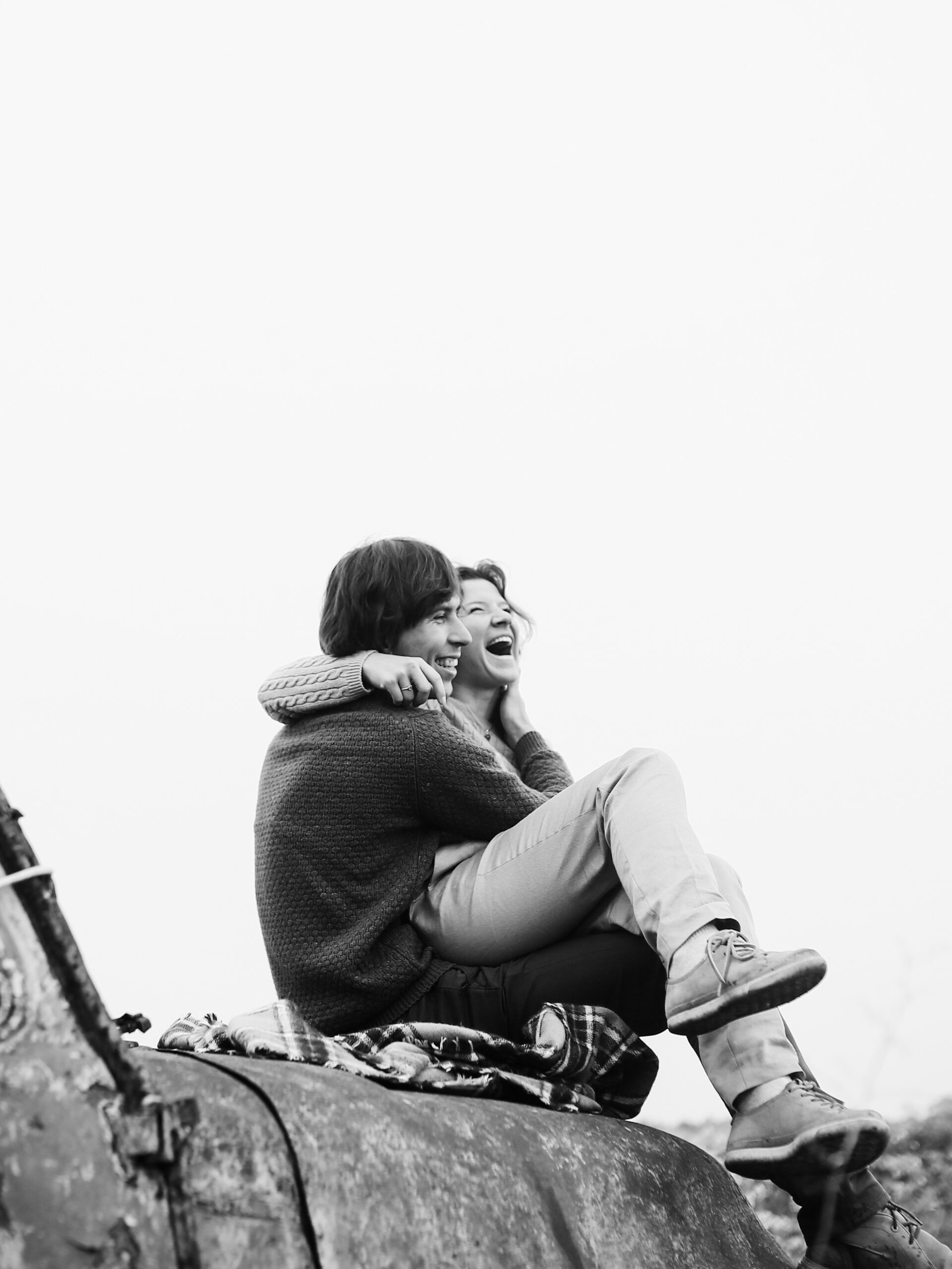 Stylish couple in love sit on the abandoned truck and looks happy